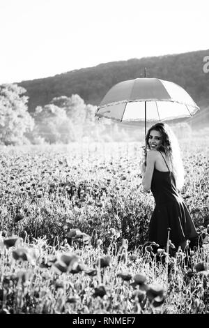 pretty happy girl in field of poppy seed with umbrella Stock Photo