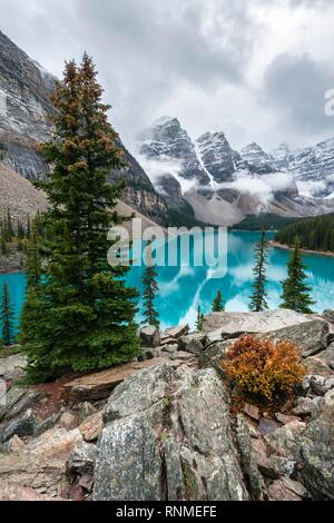 Clouds hanging between the mountain peaks, reflection in turquoise glacial lake, Moraine Lake, Valley of the Ten Peaks, Rocky Mountains, Banff Nationa Stock Photo