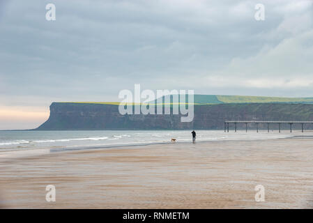 Dog walker on the beach at Saltburn-by-the-sea, North Yorkshire, England Stock Photo