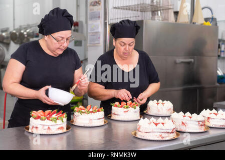 Mixed Race female pastry chef holding cake Stock Photo - Alamy