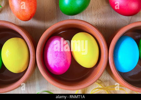 Brightly colored closeup easter eggs in clay bowls, holiday background Stock Photo