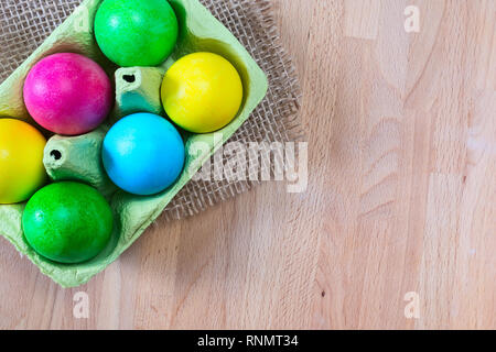 Brightly colored bow decorated easter eggs in egg carton holder, holiday background Stock Photo