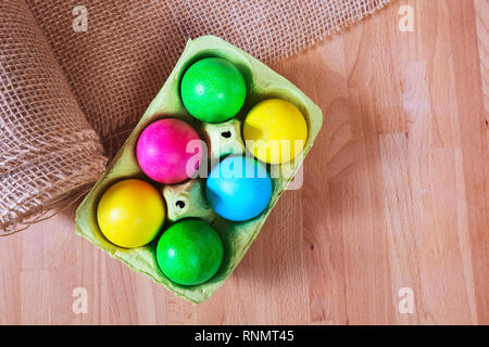 Brightly colored bow decorated easter eggs in egg carton holder, holiday background Stock Photo