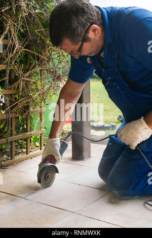 Man with grinder cutting a tile on veranda outdoor Stock Photo