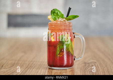 Refreshing Cold Raspberry Lemonade with Basil in mason jar with wooden background Stock Photo