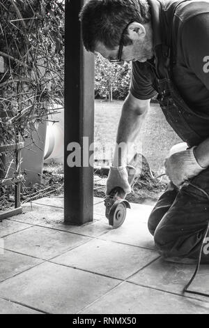 Man with grinder cutting a tile on veranda outdoor Stock Photo