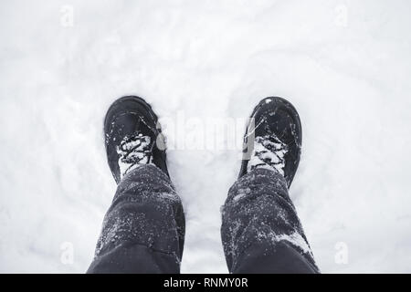 Close up photo of male feet in black shoes standing on snowy ground, first person view Stock Photo