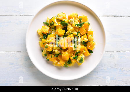 Stir-fried pumpkin with eggs on plate over white wooden background. Pumpkin and egg stir fry in thai style. Top view, flat lay Stock Photo