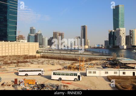 DUBAI, UAE - NOVEMBER 22, 2017: Ongoing development of Business Bay in Dubai, United Arab Emirates. White buses bring migrant construction workers to  Stock Photo