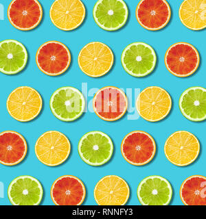 Multicolored vibrant lemon, green lime and red orande slices pattern on turquoise background. Minimal flat lay top view food texture Stock Photo