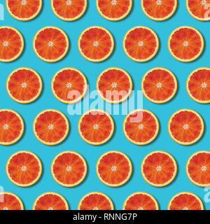 Red orange slices pattern on vibrant turquoise color background. Minimal flat lay top view food texture Stock Photo