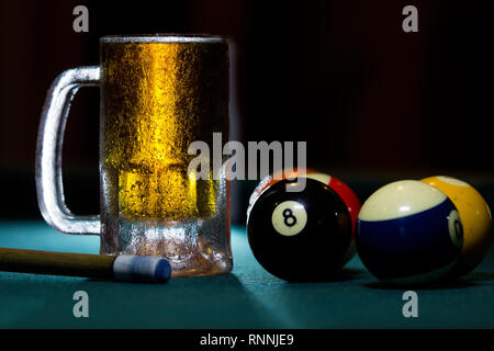 close up isolated cold frozen beer mug with billiard cues and balls on black background Stock Photo