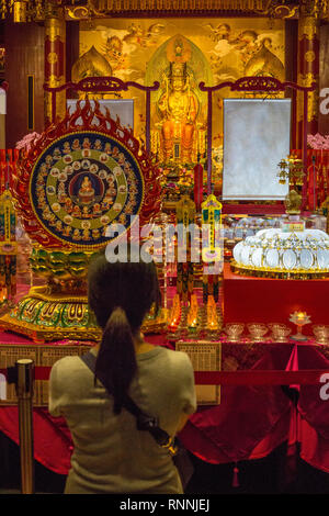 Woman Praying at Entrance to Prayer Hall, Buddha Tooth Relic Temple, Singapore.  Maitreya Buddha in background.