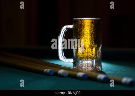 isolated cold frozen beer mug with billiard cues on black background Stock Photo