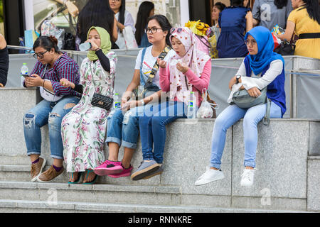 Young Singaporean Women in Conservative and Casual Western Clothes Sitting  outside ION Mall. Singapore, Orchard Road Street Scene Stock Photo - Alamy