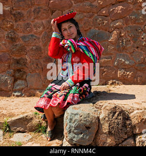 Young indigenous quechua girl in traditional clothing in front of an Inca wall of the inca ruin Tipon near Cusco, Peru. Stock Photo