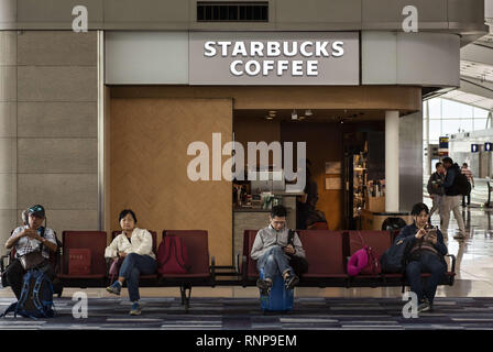 Hong Kong. 17th Feb, 2019. Passengers are seen seated next to a coffee house chain Starbucks shop at Hong Kong International Airport runway. Credit: Miguel Candela/SOPA Images/ZUMA Wire/Alamy Live News Stock Photo