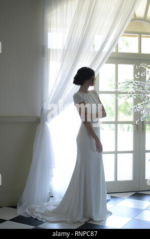 A young pensive couple have a traditional English White Wedding, they are both dark haired and good looking but seem unhappy Stock Photo