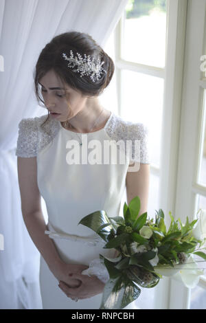 A young pensive couple have a traditional English White Wedding, they are both dark haired and good looking but seem unhappy Stock Photo