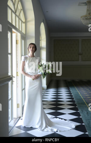 A young pensive couple have a traditional English White Wedding, they are both dark haired and good looking but seem unhappy Stock Photo