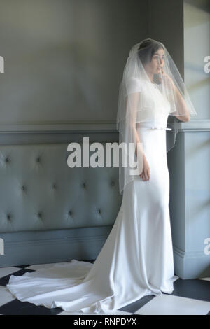 A young pensive couple have a traditional English White Wedding, they are both dark haired and good looking but seem unhappy Stock Photo
