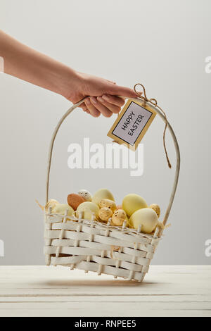 Cropped view of woman holding straw basket with easter chicken and quail eggs, card with happy easter lettering Stock Photo