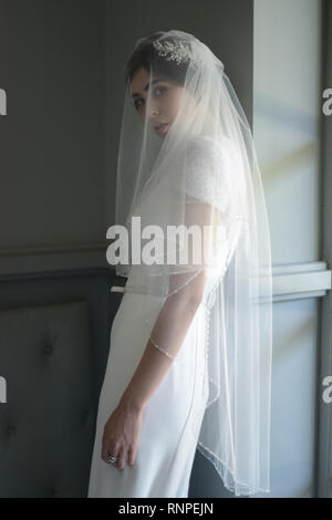 A young pensive couple have a traditional English White Wedding, they are both dark haired and good looking but seem unhappy Stock Photo
