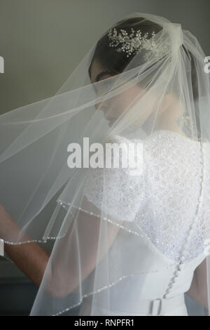 A young pensive couple have a traditional English White Wedding, they are both dark haired and good looking but seem unhappy Stock Photo