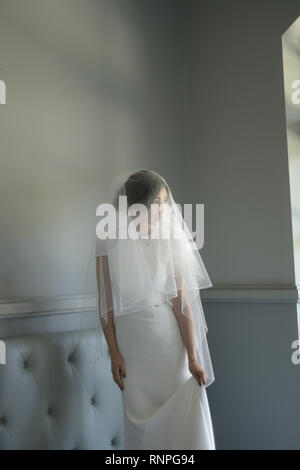 A young pensive couple have a traditional English White Wedding, they are both dark haired and good looking but seem unhappy Stock Photo