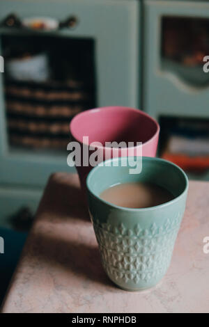 Two cups of coffee, pink and green, standing on a stone table Stock Photo