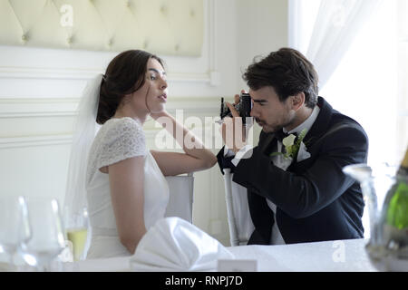 A young pensive couple have a traditional English White Wedding, they are both dark haired and good looking but seem unhappy Stock Photo