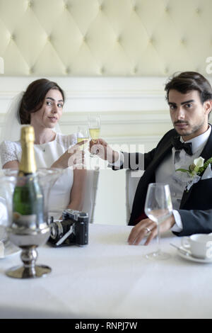 A young pensive couple have a traditional English White Wedding, they are both dark haired and good looking but seem unhappy Stock Photo