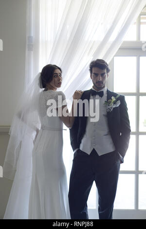 A young pensive couple have a traditional English White Wedding, they are both dark haired and good looking but seem unhappy Stock Photo