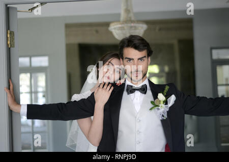 A young pensive couple have a traditional English White Wedding, they are both dark haired and good looking but seem unhappy Stock Photo