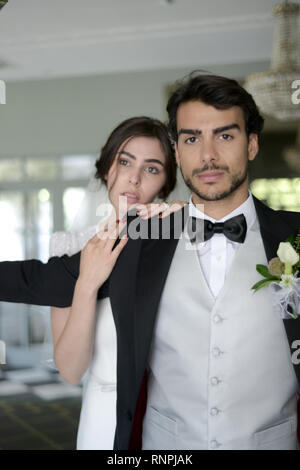 A young pensive couple have a traditional English White Wedding, they are both dark haired and good looking but seem unhappy Stock Photo