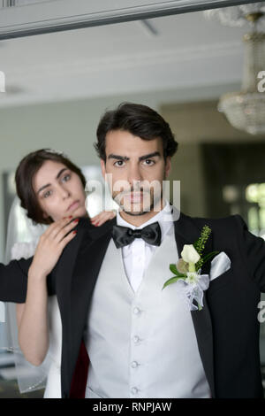 A young pensive couple have a traditional English White Wedding, they are both dark haired and good looking but seem unhappy Stock Photo