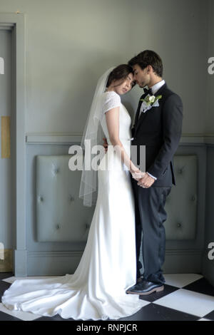 A young pensive couple have a traditional English White Wedding, they are both dark haired and good looking but seem unhappy Stock Photo