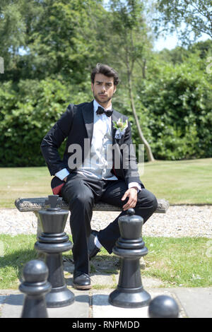 A young pensive couple have a traditional English White Wedding, they are both dark haired and good looking but seem unhappy Stock Photo