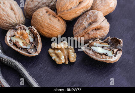 Walnuts with nutcracker, on black surface Stock Photo
