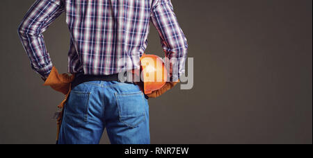Builder man in plaid shirt and gloves wearing and holding helmet Stock Photo