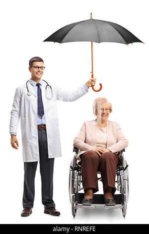 Full length portrait of a male doctor holding an open umbrella over the head of a senior woman in a wheelchair isolated on white background Stock Photo