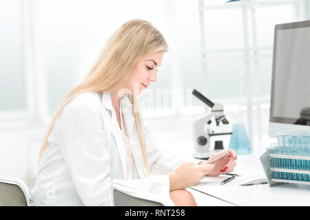 female scientist uses smartphone in the workplace Stock Photo