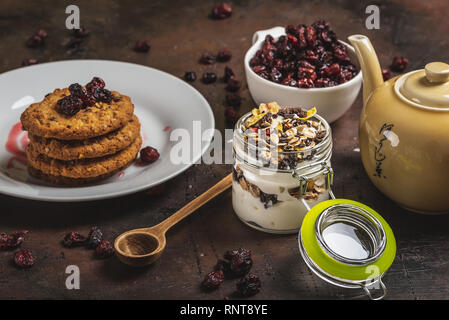 Horizontal photo with top view on white yogurt. Yogurt is in small glass jar with metal lock and sealed cover. Muesli with dried food is layered in an Stock Photo