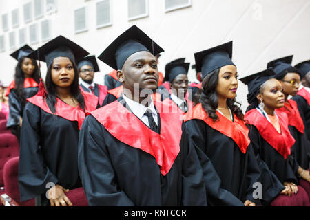 GRODNO, BELARUS - JUNE, 2018: Foreign african medical students in square academic graduation caps and black raincoats during commencement with diploms Stock Photo