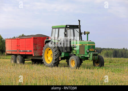 Salo, Finland - September 8, 2018: John Deere 3140 farm tractor and agricultural trailer full of harvested rapeseed on a beautiful day of autumn.