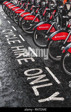 Santander London Bike hire parked in charging racks, otherwise known as Boris bikes. Used for commuting, tourists and for fun, 11,500 bikes available. Stock Photo