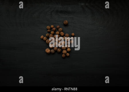 Close-up image of dried pimento berries on black wood background, view above Stock Photo