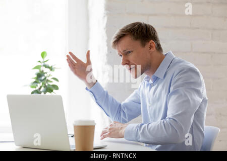 Irritated businessman having problems with computer gesticulating feels angry  Stock Photo