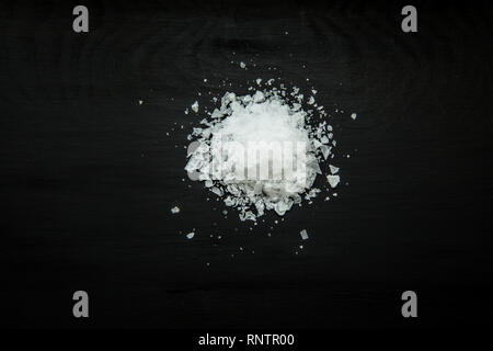 Close-up image of sea salt flakes on black wood background, view above Stock Photo