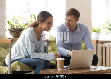 Couple of freelancers sitting on comfortable chairs working using laptop  Stock Photo